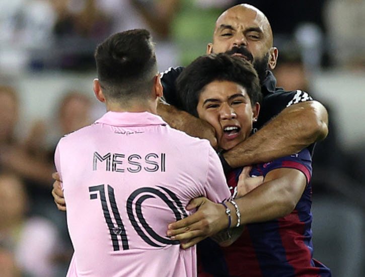 Messi's bodyguard restrains pitch invader.